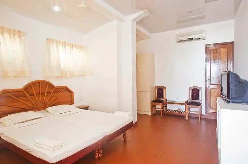 Clean air-conditioned guest room layout with twin beds and white linens at Hotel Marine Palace Kovalam.