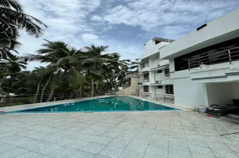 Outdoor swimming pool area next to the modern accommodation wing at Hotel Marine Palace Kovalam.