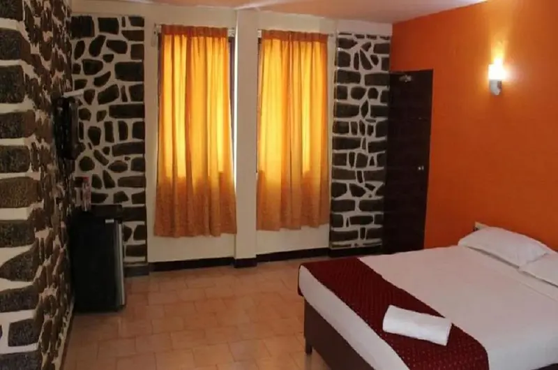 Comfortable air-conditioned guest room featuring a decorative stone accent wall at New Kovalam Beach Hotel.