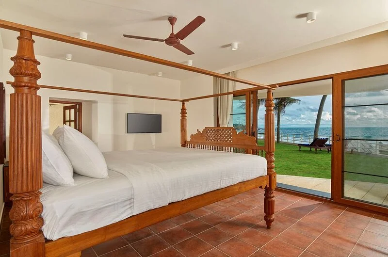 Premium suite room featuring a traditional wooden four poster bed at Rockholm Kovalam.