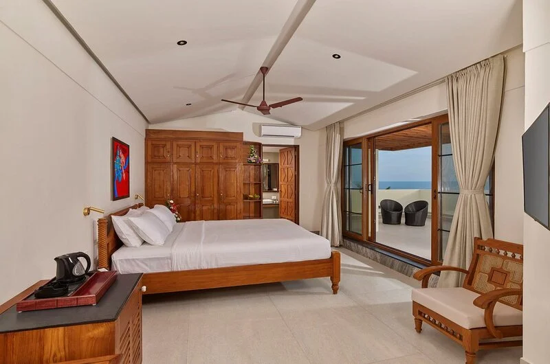 Luxury oceanfront suite room interior featuring warm wooden flooring at Rockholm Kovalam.