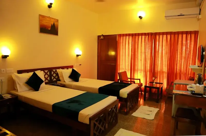 Comfortable air conditioned twin bedroom layout with warm interior lighting at Hotel Sea Face Kovalam.