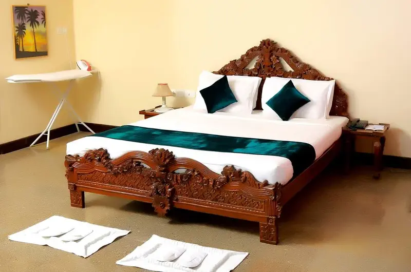 Premium deluxe double bedroom accommodation featuring an ornate wooden headboard at Hotel Sea Face Kovalam.
