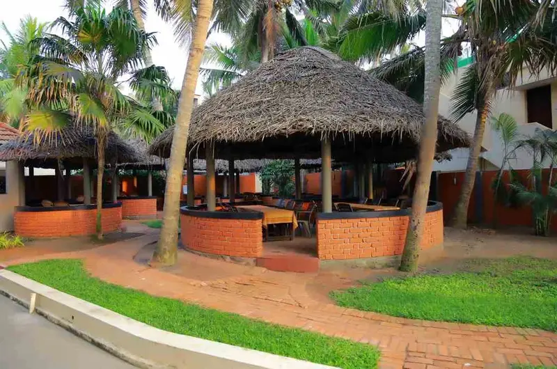 Traditional thatch roof poolside restaurant and outdoor dining lounge at Hotel Sea Face Kovalam.