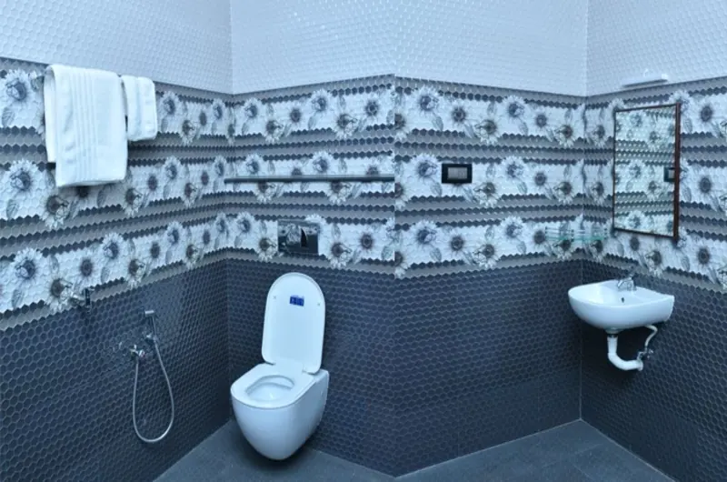 Clean attached bathroom interior featuring a western toilet and tiled walls at Bougainvillea Homestay Kovalam.