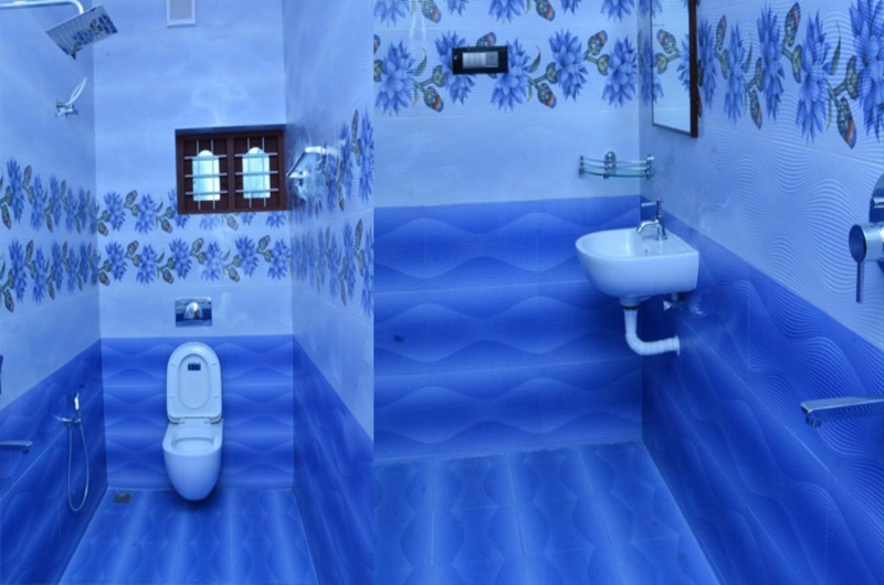 Modern guest bathroom layout with a ceramic washbasin and blue tiled walls at Bougainvillea Homestay Kovalam.