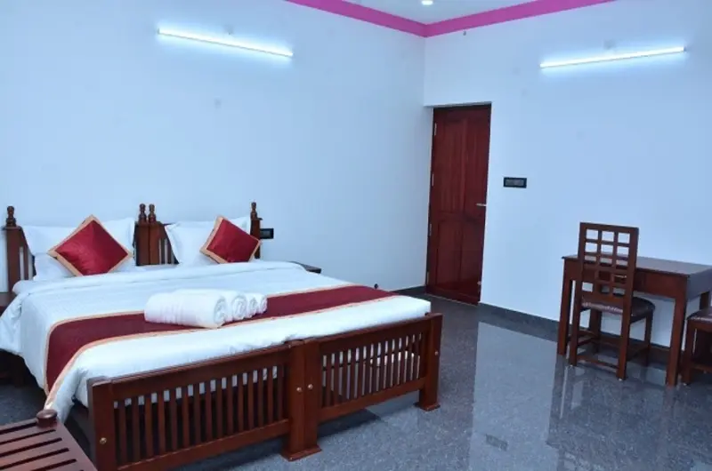 Deluxe double bedroom accommodation with clean white linens and tiled flooring at Bougainvillea Homestay Kovalam.