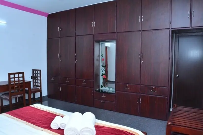 Cozy guest room interior featuring a double bed and warm wooden wall wardrobes at Bougainvillea Homestay Kovalam.