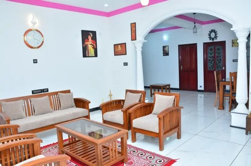 Welcoming common sitting lounge featuring traditional wooden sofa chairs at Bougainvillea Homestay Kovalam.
