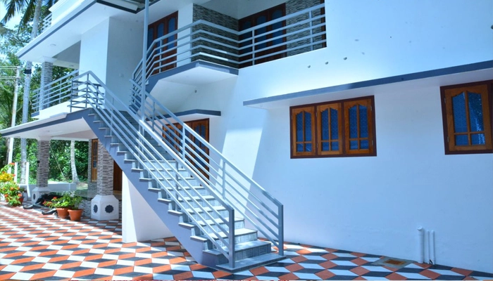 Modern white exterior building with step access and steel balcony railings at Bougainvillea Homestay Kovalam.