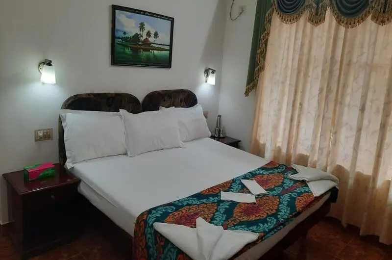 Deluxe double bedroom interior featuring clean white linens and ambient lighting at Gokulam Homestay Kovalam.