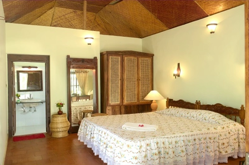 Spacious deluxe cottage room interior featuring classic wooden furnishings at Soma Manaltheeram Ayurvedic Hospital & Research Centre