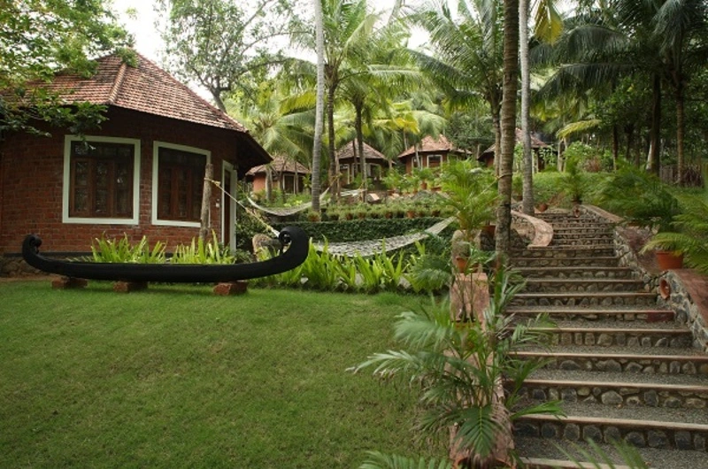 Traditional round brick cottage accommodation surrounded by greenery at Soma Manaltheeram Ayurvedic Hospital & Research Centre