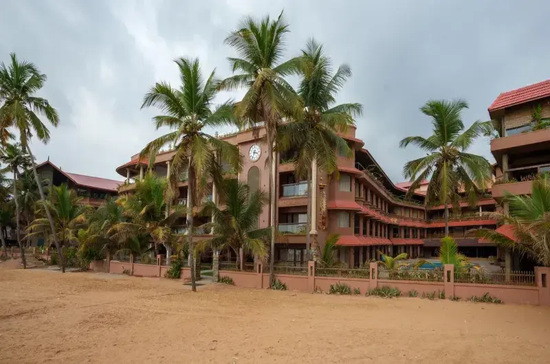 Grand multi-story building of Uday Samudra Leisure Beach Hotel Kovalam alongside a large outdoor swimming pool.