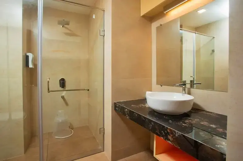 Contemporary attached bathroom interior with a granite countertop washbasin at The Neelakanta Beach Resort Kovalam.
