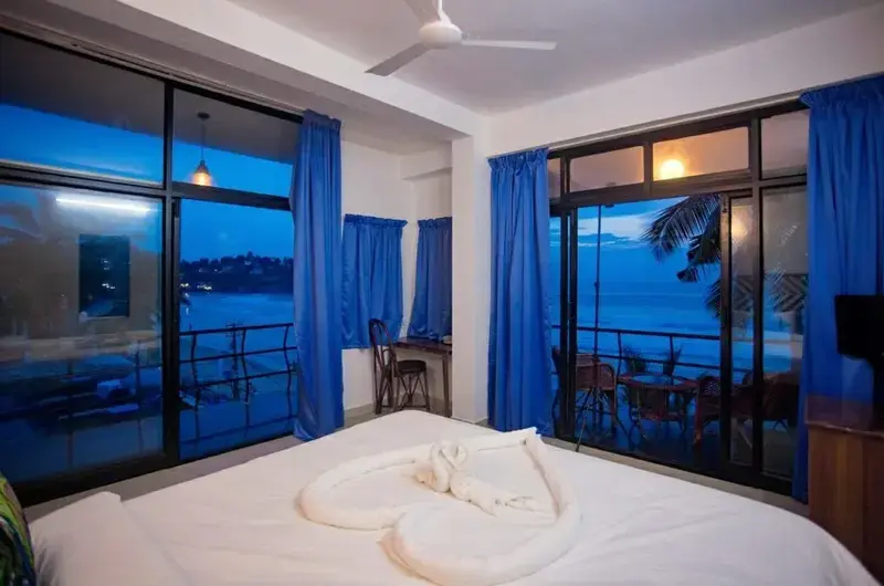 Romantic oceanfront honeymoon suite accommodation featuring wide panoramic windows at The Neelakanta Beach Resort.