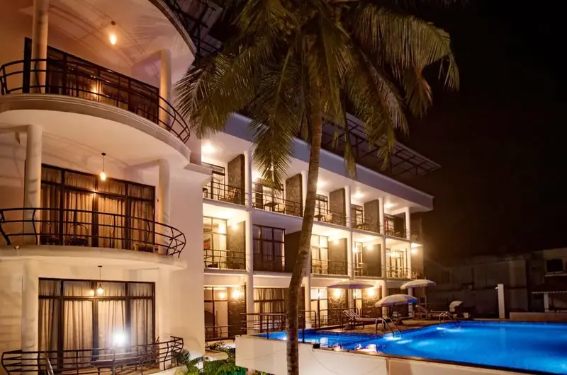 Illuminated multi-story building and outdoor swimming pool at night at The Neelakanta Beach Resort Kovalam.