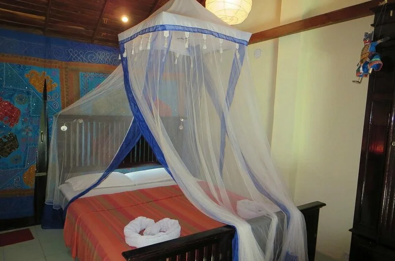 Deluxe double bedroom accommodation featuring a decorative canopy mosquito net at Maharaju Palace Kovalam.
