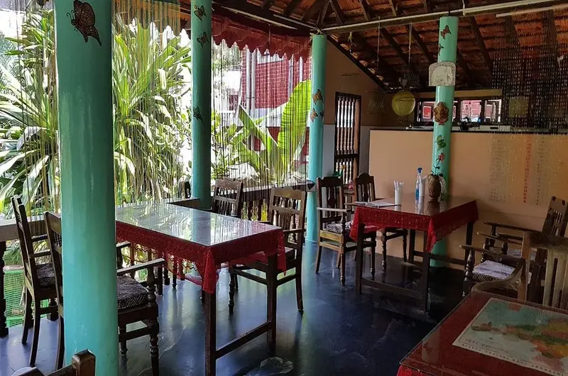 Traditional wooden pillared porch veranda and outdoor dining space at Maharaju Palace Kovalam.