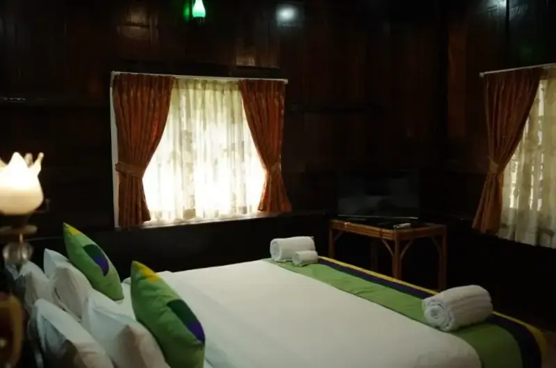 Cozy traditional guest room interior with wooden windows at Gods Own Country Ayurveda Resort