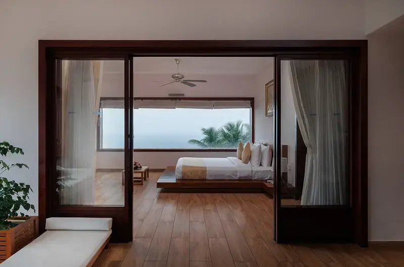 Luxury sea face suite bedroom with large glass windows at Gokulam Grand Turtle on the Beach Kovalam
