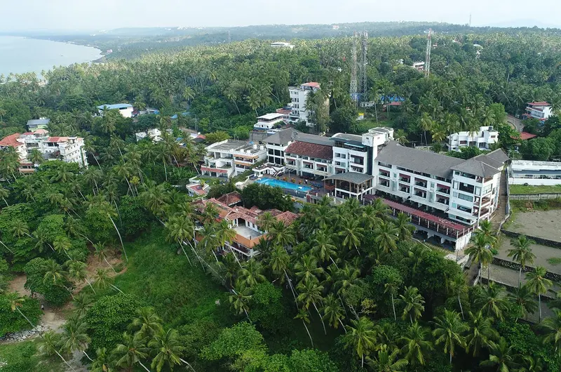 Aerial view of Gokulam Grand Turtle on the Beach resort property surrounded by palm trees