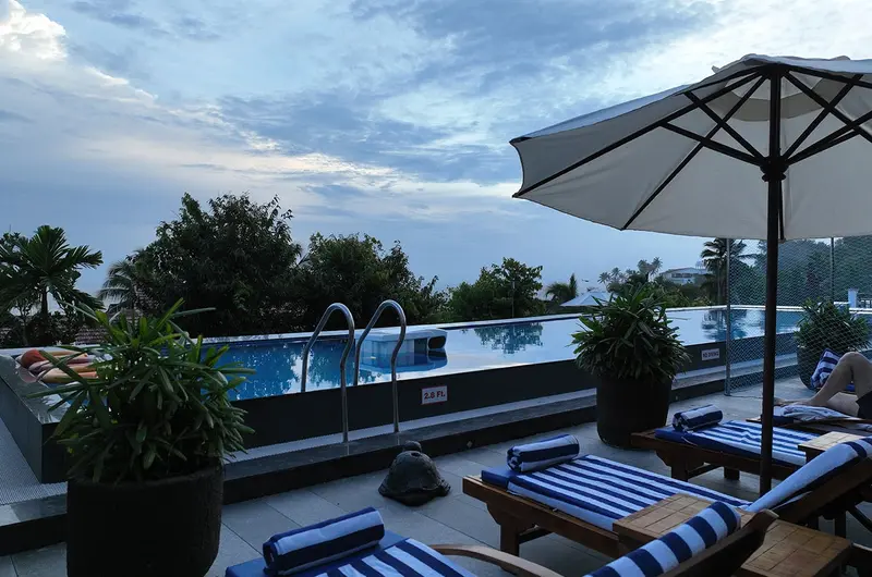 Outdoor poolside seating area with umbrellas and lounge chairs at Gokulam Grand Turtle on the Beach