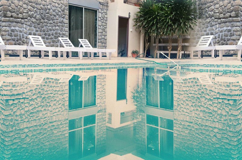 Sparkling outdoor swimming pool with poolside loungers at New Kovalam Beach Hotel.