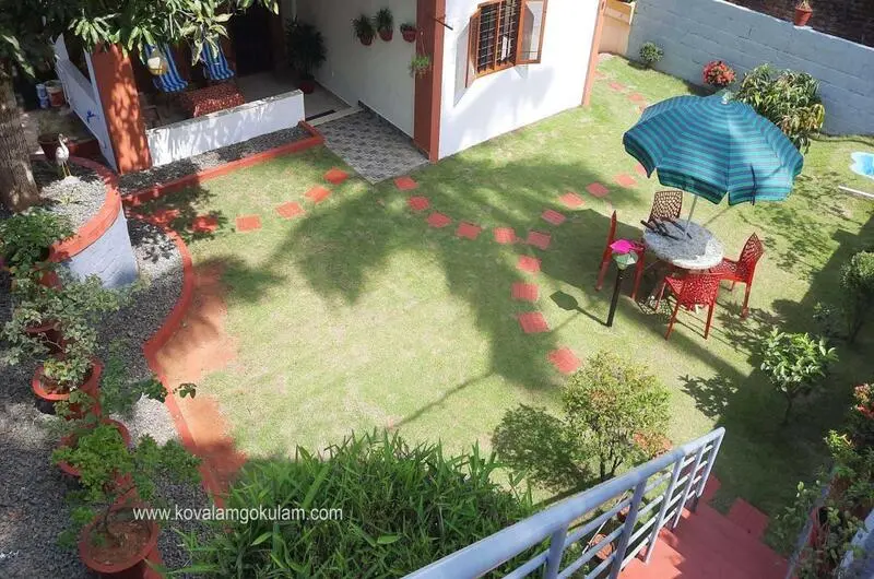 Paved garden pathway and green outdoor lawn area at Gokulam Homestay Kovalam.