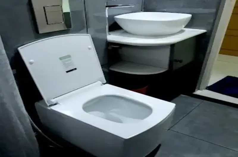 Modern attached bathroom interior at The Nest Homestay Kovalam featuring a clean white washbasin and toilet.