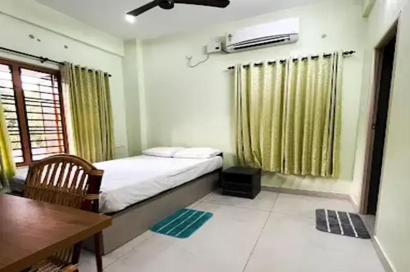 Premium air-conditioned guest room at The Nest Homestay Kovalam featuring a large bed and side tables.