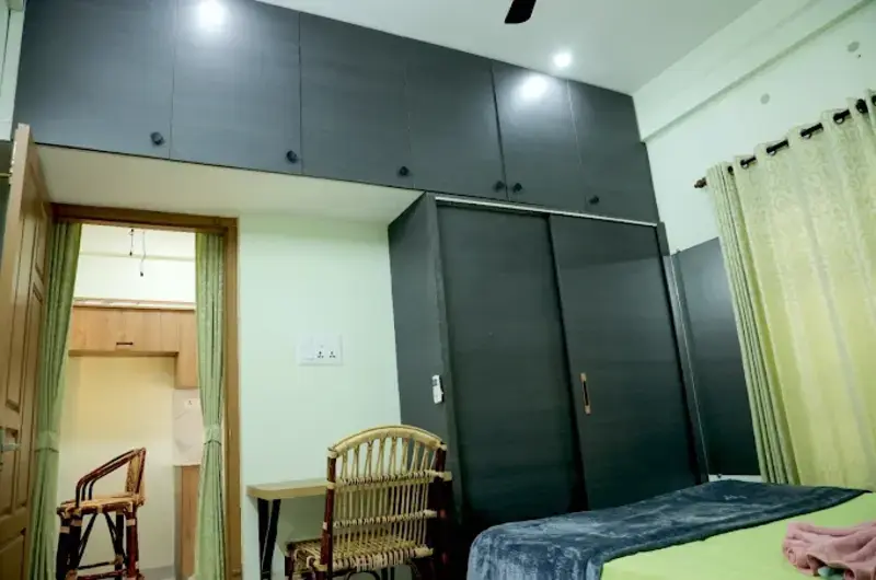Clean AC guest bedroom accommodation at The Nest Homestay Kovalam featuring a spacious wardrobe and a vanity mirror.