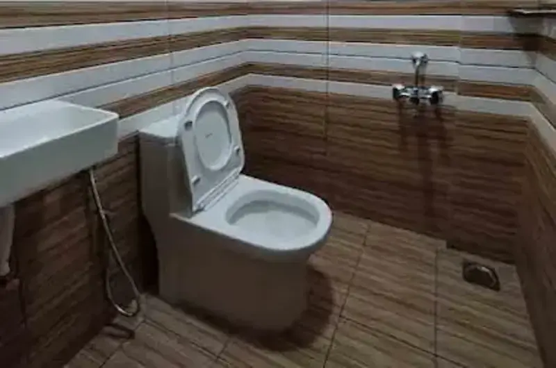 Clean attached guest bathroom interior with modern ceramic wall tiles and a western toilet at Greenview Homestay Kovalam.