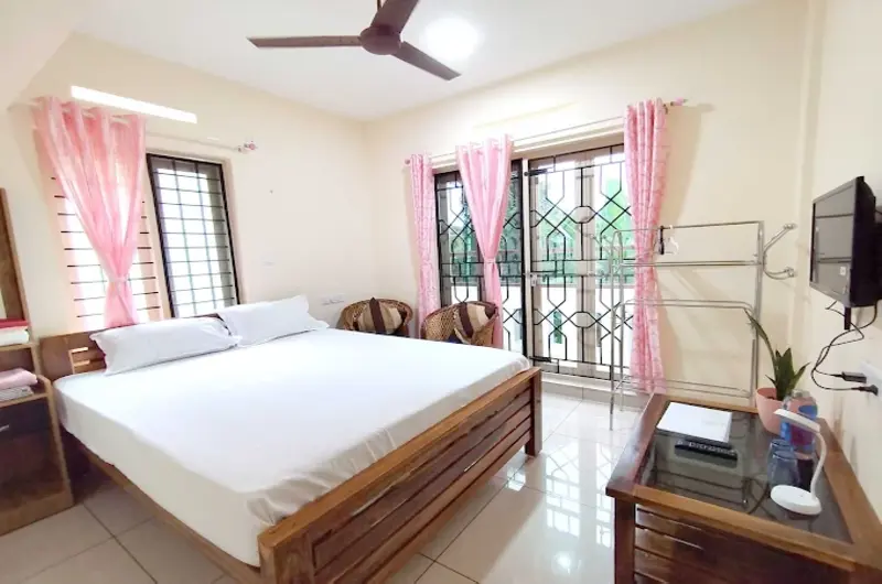 Premium double bedroom interior leading to a private outdoor balcony at Greenview Homestay Kovalam.