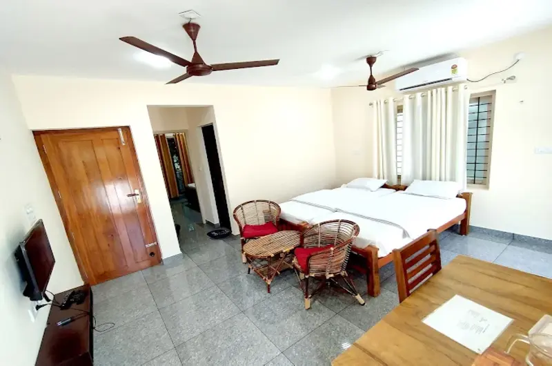 Deluxe guest bedroom accommodation featuring clean linens, an attached bathroom, and an AC unit at Greenview Homestay Kovalam.