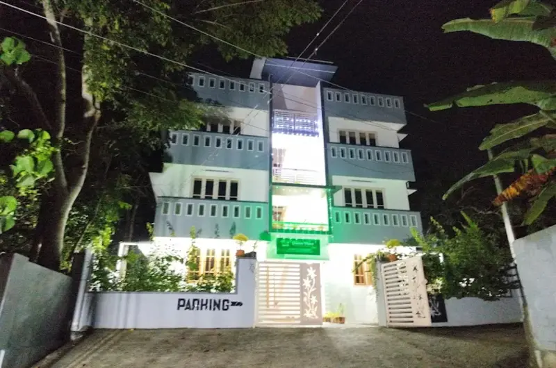 Night view of the illuminated exterior building of Greenview Homestay Kovalam with a gated entrance.