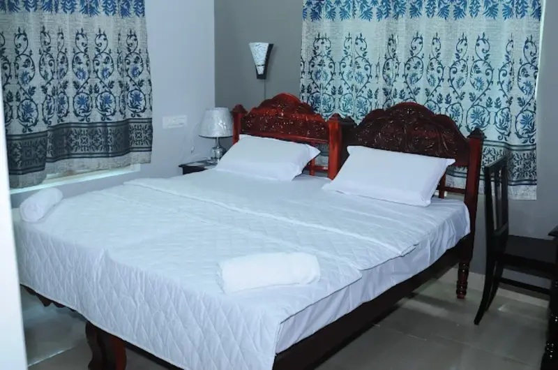 Comfortable budget air conditioned guest bedroom with large windows at Jeevan Homestay Kovalam.