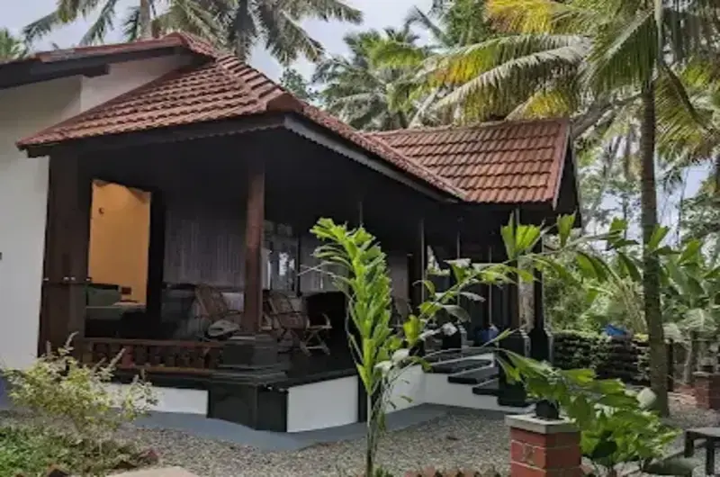 Heritage style wooden cottage with a gabled clay tile roof at Jeevan Homestay Kovalam.