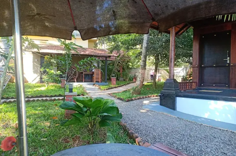 Paved outdoor garden pathway surrounded by lush tropical landscaping at Jeevan Homestay Kovalam.