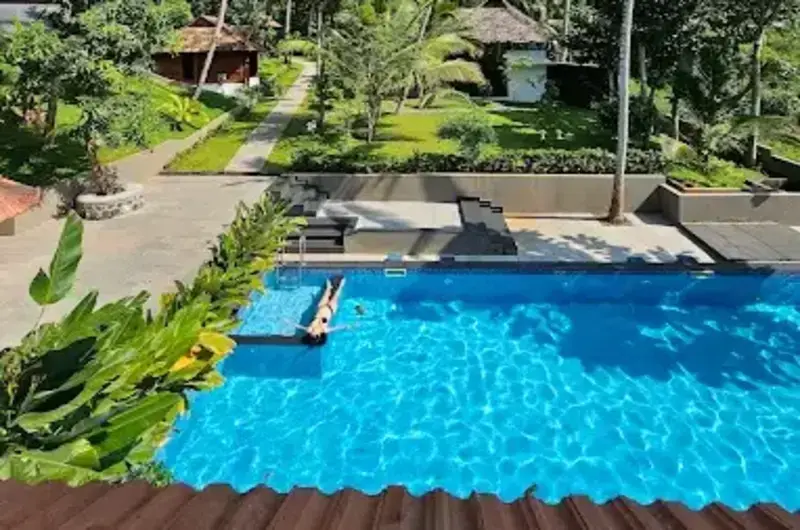 Clean blue outdoor swimming pool and paved courtyard walkway at Jeevan Homestay Kovalam.