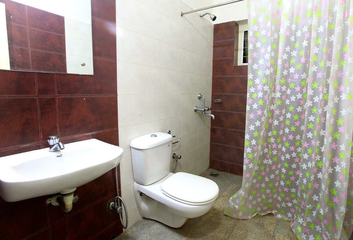 Clean attached guest bathroom interior featuring a western toilet and a white washbasin at Little Paradise Homestay Kovalam.