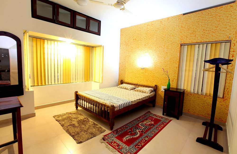 Deluxe guest room interior featuring a double bed, clean linens, and a floor lamp at Little Paradise Homestay Kovalam.