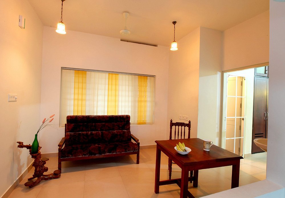 Cozy indoor living room and guest sitting lounge featuring wooden furniture at Little Paradise Homestay Kovalam.