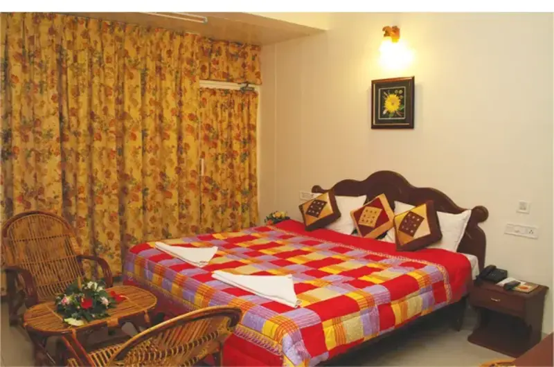 Deluxe double bedroom with red patterned linens at Rock N Beach Kovalam