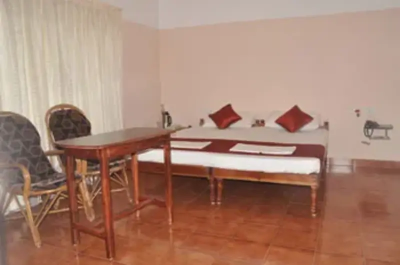 Deluxe twin bedroom setup with wooden flooring and seating area at Vayalkara Seaside Resort