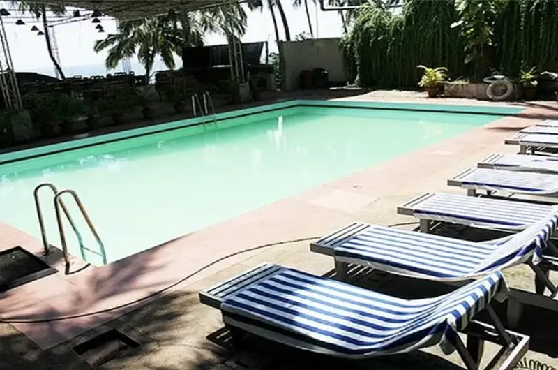 Outdoor swimming pool with lounge chairs at Raja Hotel Kovalam