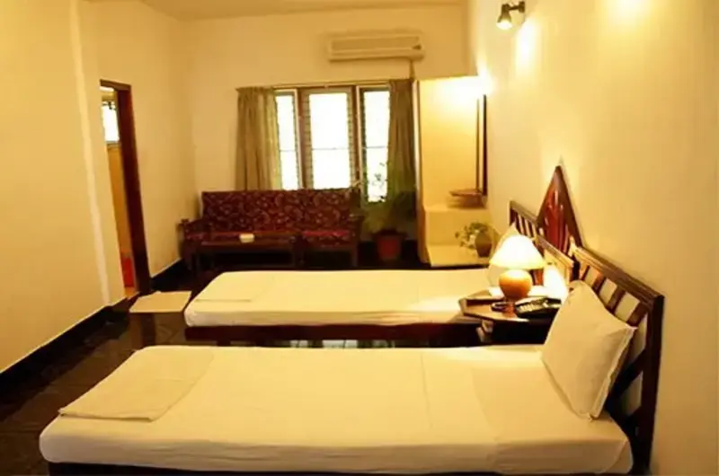 Deluxe twin bedroom setup with warm indoor lighting at Raja Hotel Kovalam