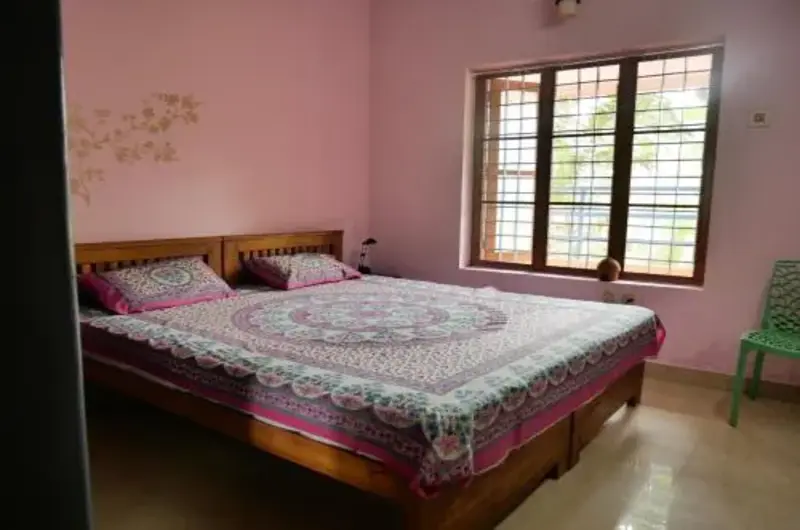 Comfortable guest bedroom with double bed and window at Padmini House Kovalam