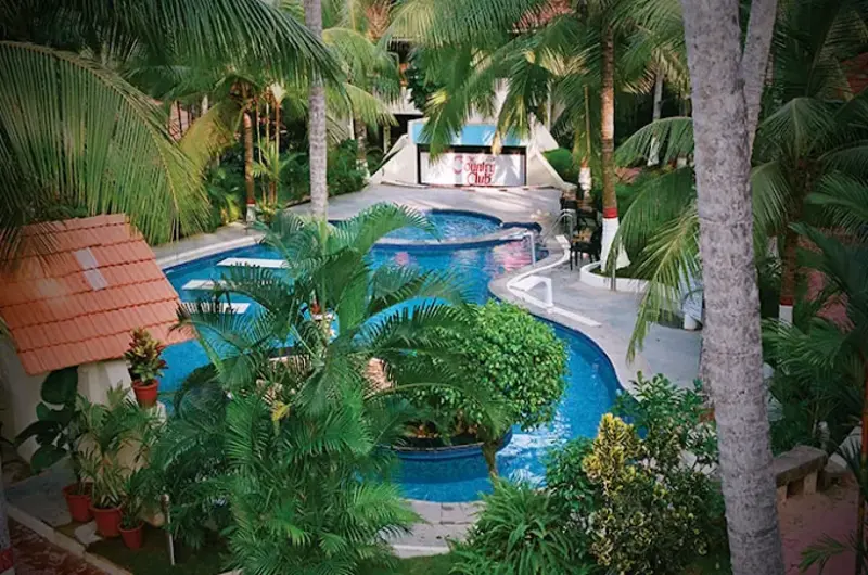 Large outdoor swimming pool surrounded by lush tropical greenery at Country Club Kovalam Beach