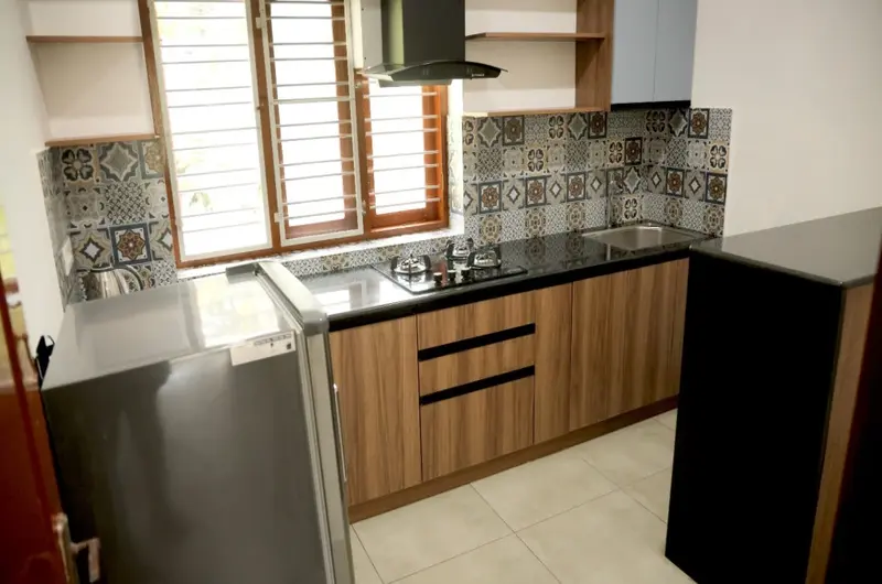 Modern modular kitchen with wooden cabinets and appliances at Sobha Mandiram Kovalam